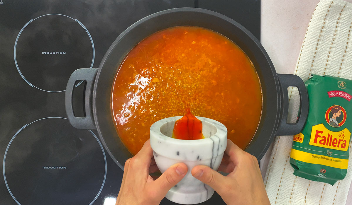 Agregar caldo y azafrán en arroz con corvina