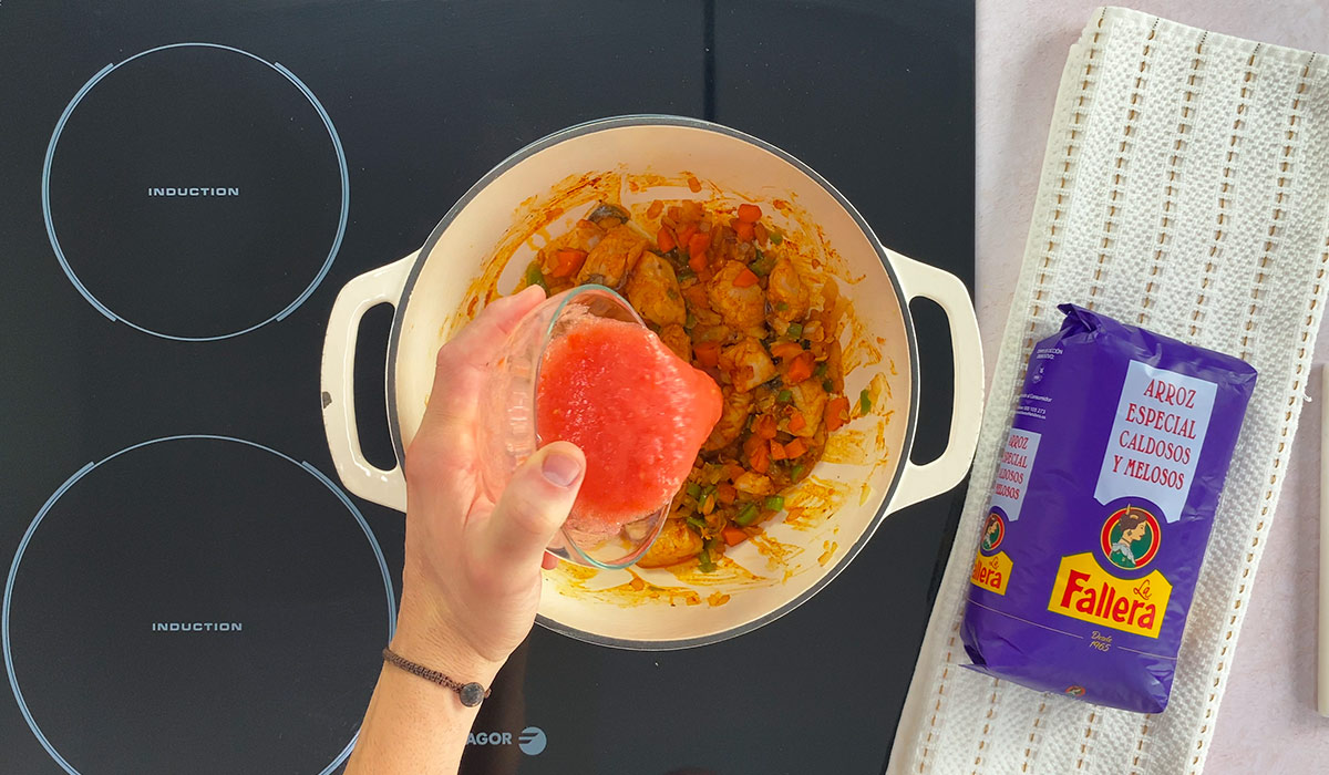 Añadir pimentón y tomate triturado en Arroz con merluza y verduras