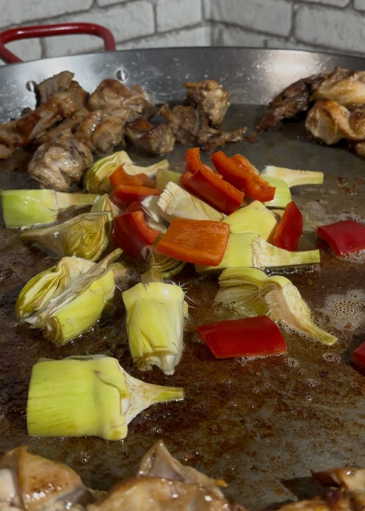 Dorar pimiento y alcachofas en paella de conejo