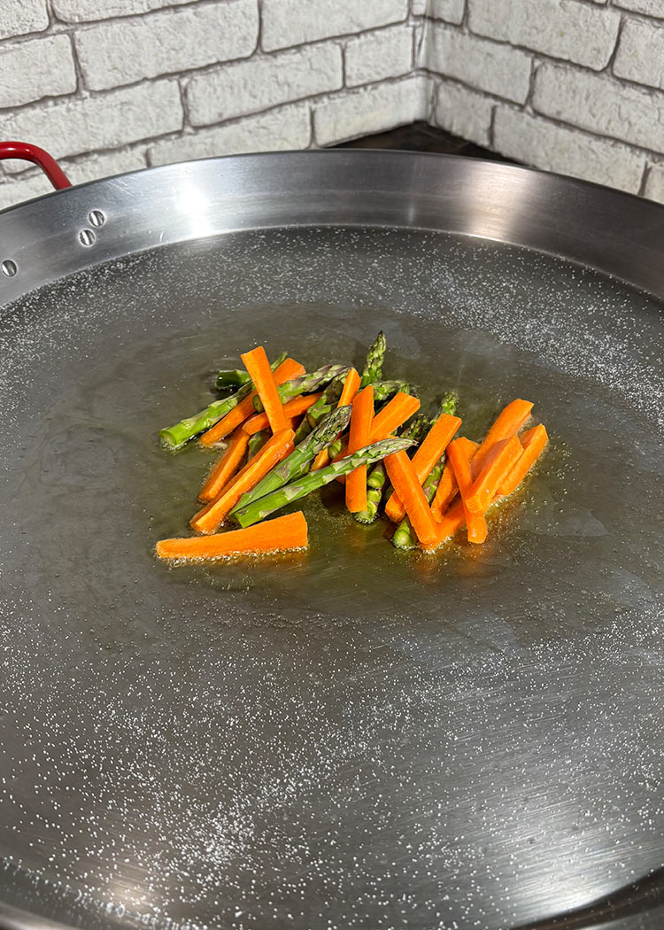 Sofreír zanahorias y espárragos en Arroz con conejo y verduras